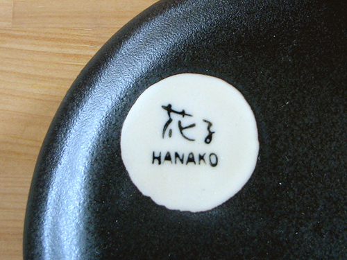黒いお皿のアップ写真「花子 ＨＡＮＡＫＯ」の名入れはゴム版使用